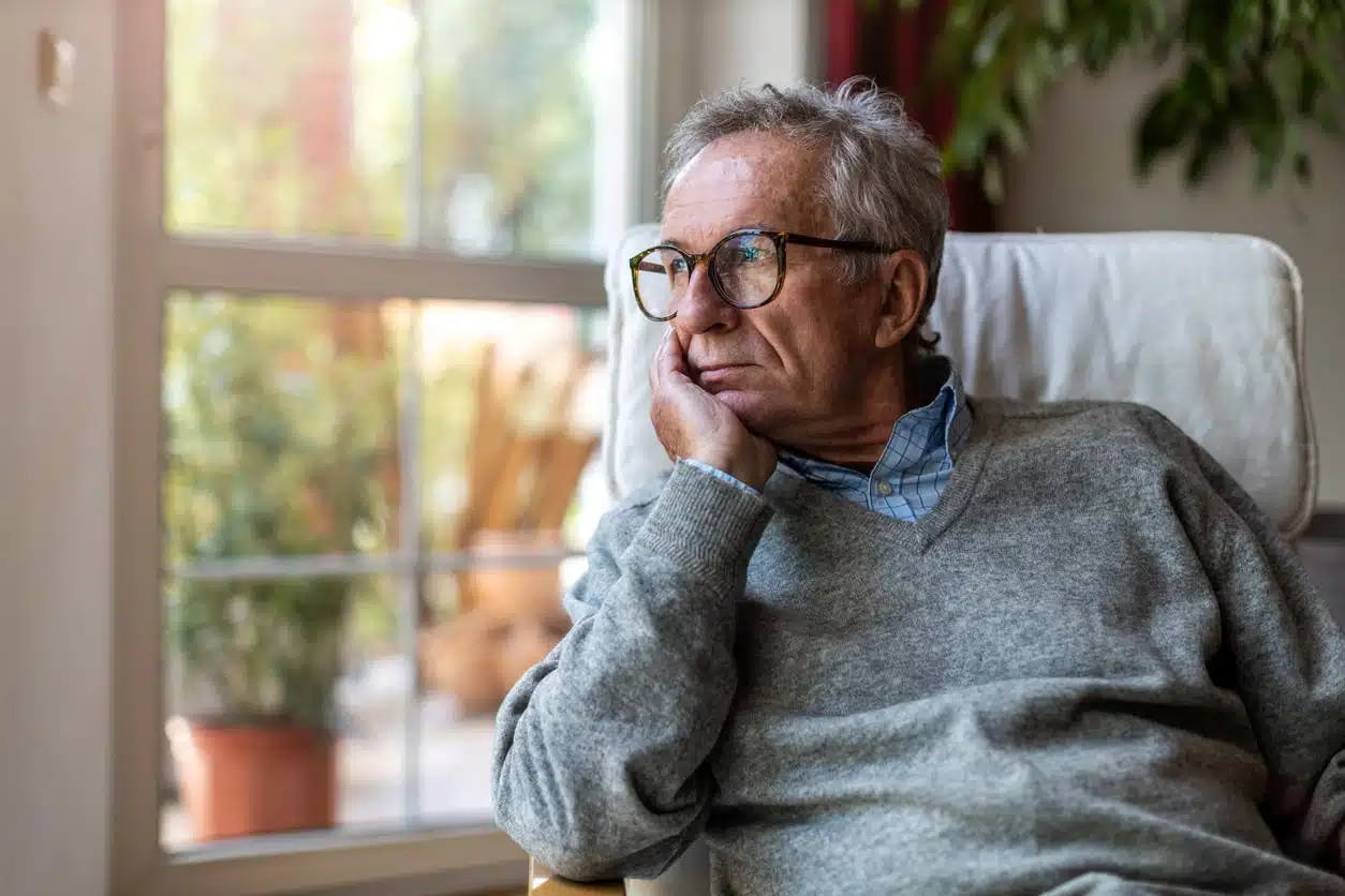 Mature man looking worried while gazing out the window