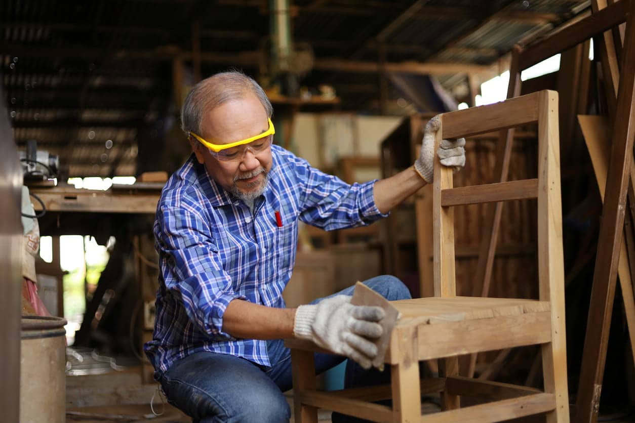 Mature man sanding a chair in a woodshop