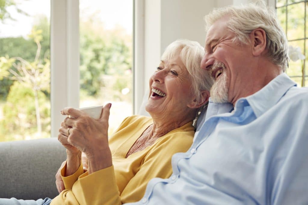 Senior couple laughing on the couch