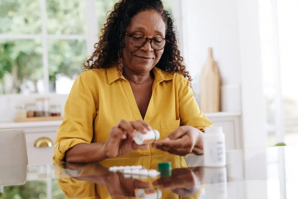 Mature woman taking medications at kitchen table